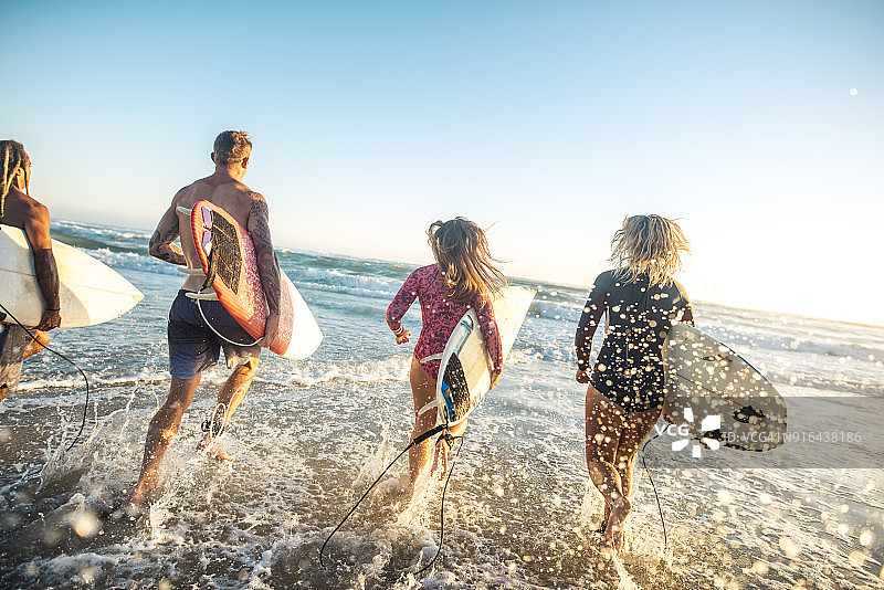 朋友们带冲浪板奔向大海图片素材
