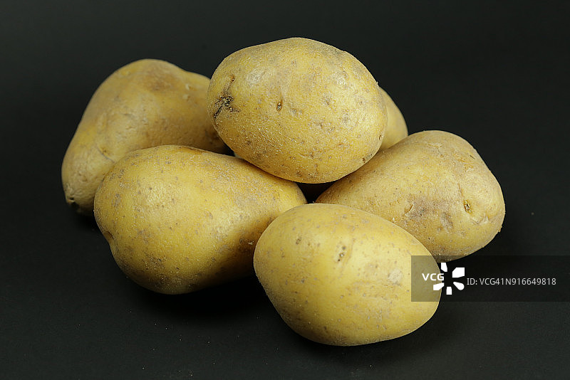 黑色背景上的生黄土豆图片素材