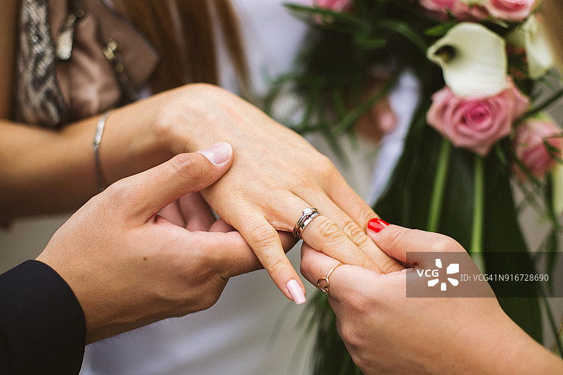 朋友们握着新娘戴着银色结婚戒指的手图片素材