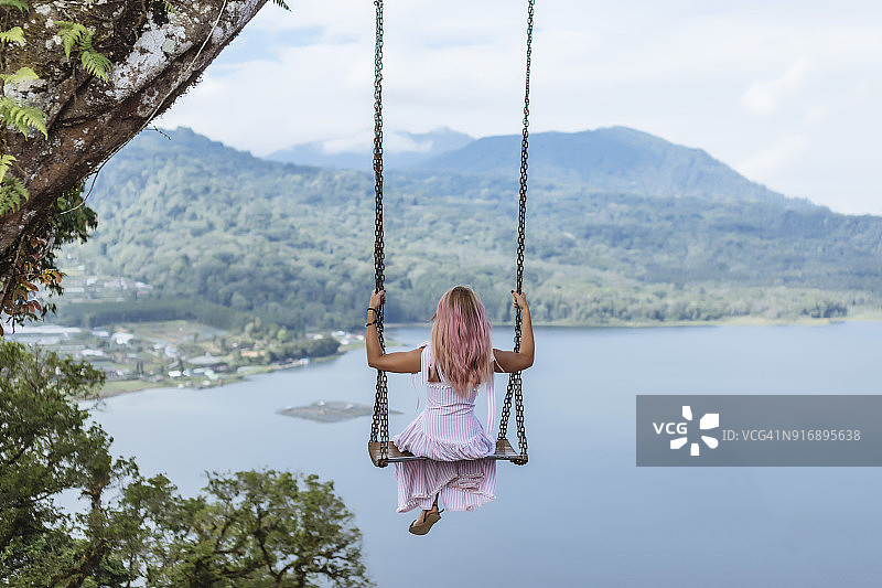印度尼西亚巴厘岛，年轻女子坐在秋千上图片素材