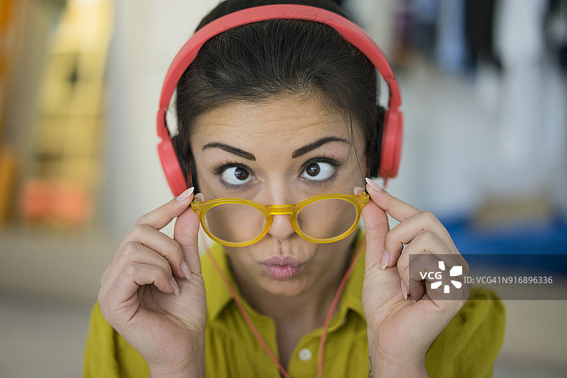 戴耳机和眼镜，做鬼脸的女子肖像图片素材