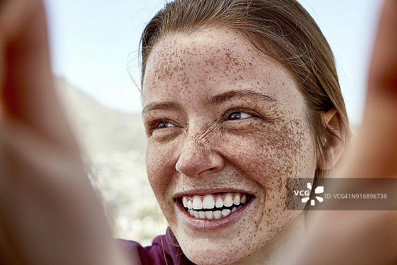 在户外有雀斑欢笑的年轻女人肖像图片素材
