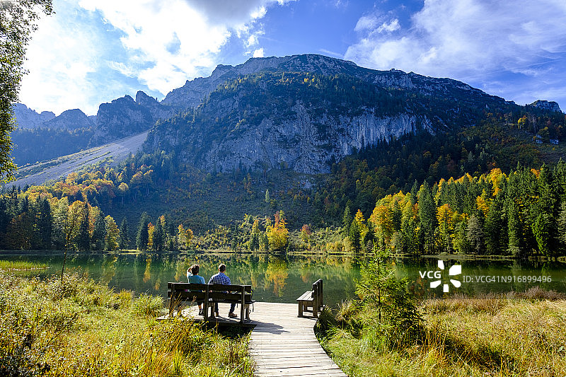 德国巴伐利亚州上巴伐利亚基姆高：因采尔，弗里尔湖，秋季徒步者坐在长椅上图片素材