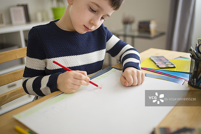 小男孩坐在桌旁做学校作业图片素材