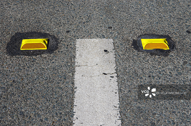 城市街道上的白色分道线和黄色塑料反光器图片素材