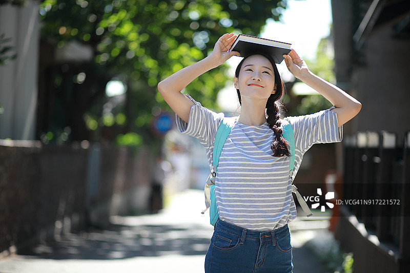 学生在户外头顶平衡书本图片素材