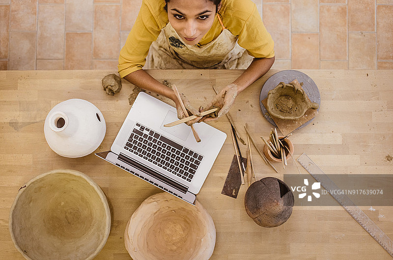 年轻女子使用笔记本电脑制作陶器图片素材