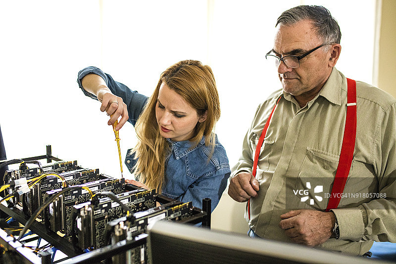 成熟工程师协助触摸并纠正加密货币视频卡的女人图片素材