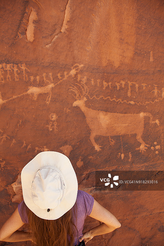 年轻女子欣赏犹他州梳状岭的岩石艺术图片素材