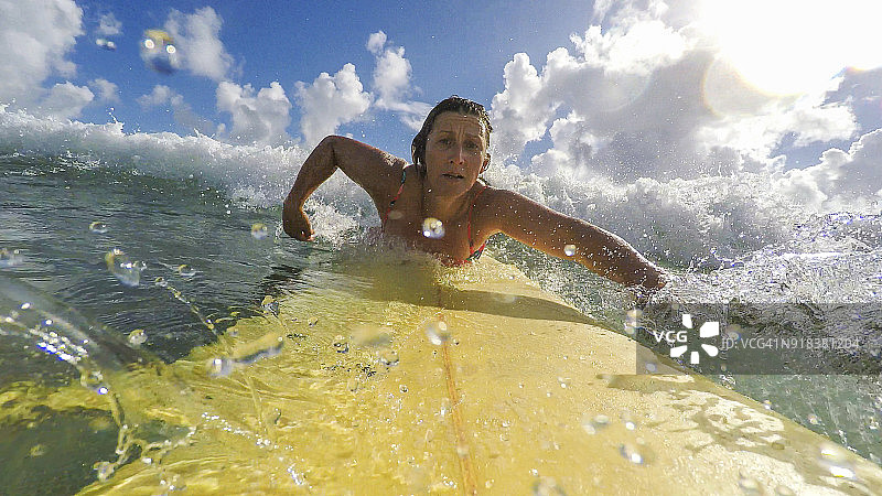 POV视角：中年妇女在海滩冲浪图片素材