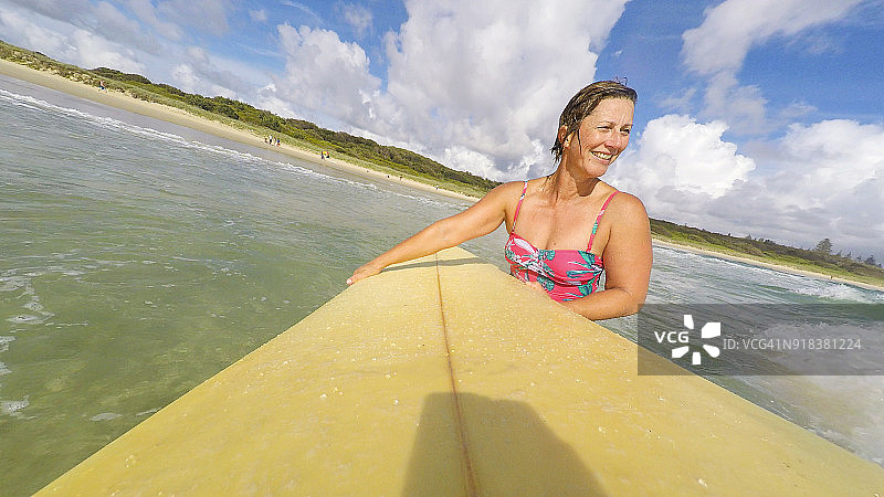 POV视角：中年妇女在海滩冲浪图片素材