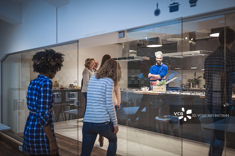 年轻厨师欢迎他的烹饪班图片素材