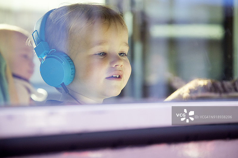 透过窗户看到戴着耳机的小男孩图片素材