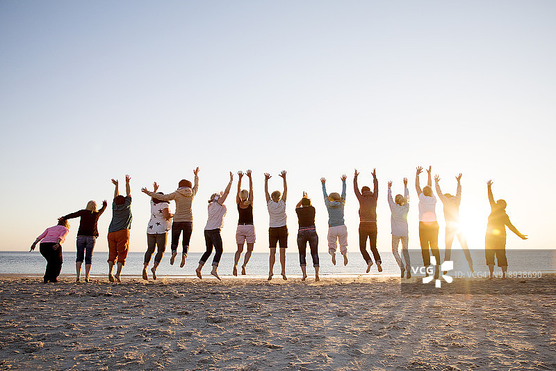阳光下在海滩上排队跳跃的朋友们图片素材