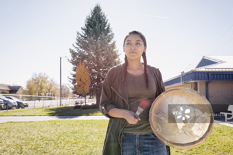 在保护区学校里打鼓的年轻美洲原住民妇女图片素材