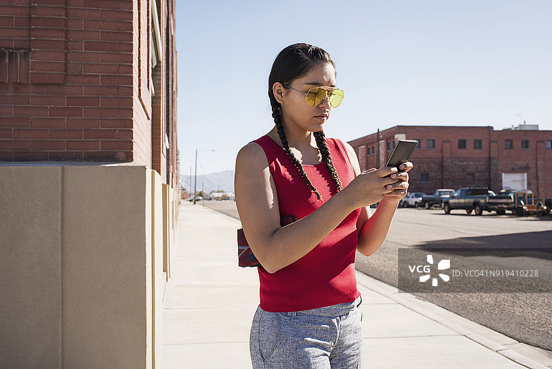 在商业区使用手机的年轻美洲原住民女性图片素材