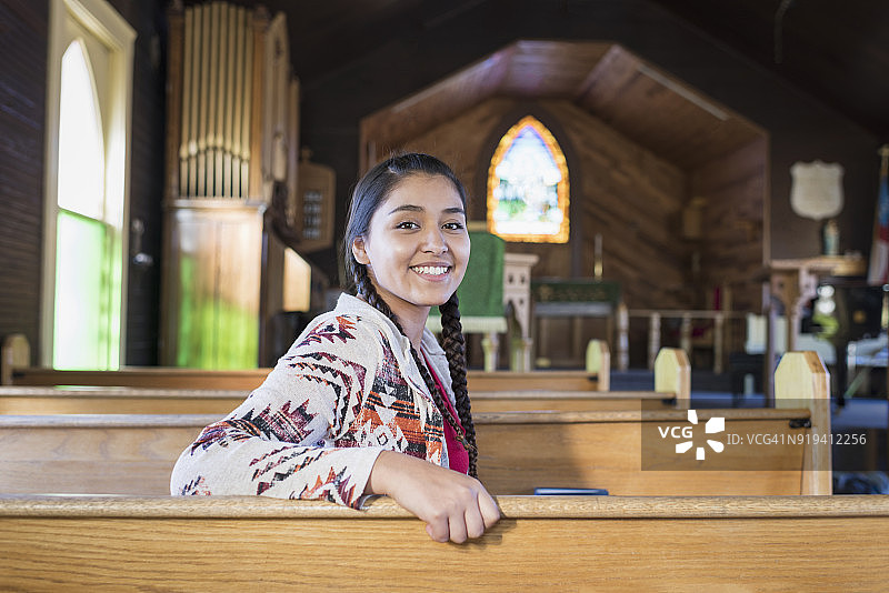 坐在教堂长椅上的年轻美洲原住民妇女图片素材