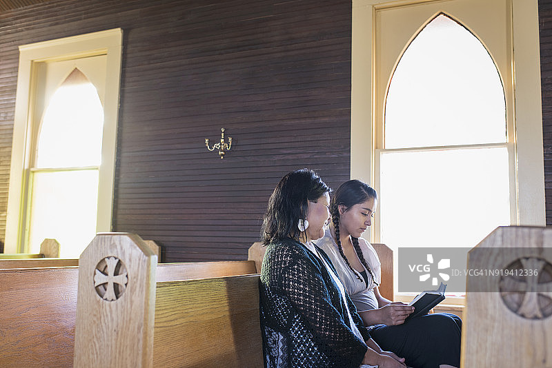 坐在教堂长椅上的年轻和年长的美洲原住民妇女图片素材