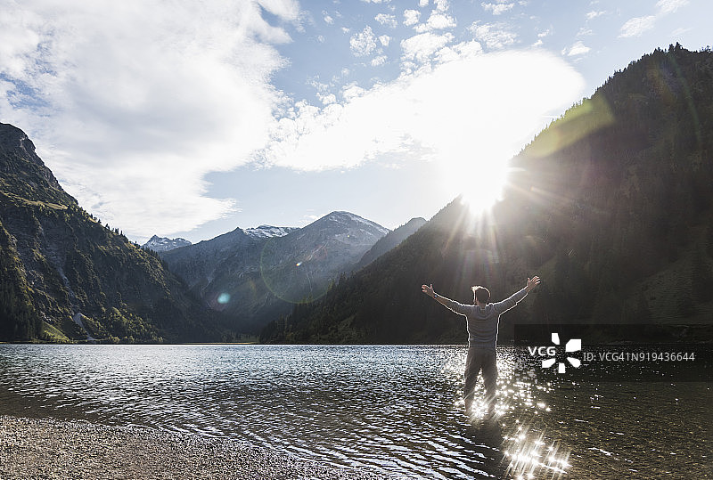 奥地利，提洛尔，徒步旅行者张开双臂站在山上的湖里图片素材