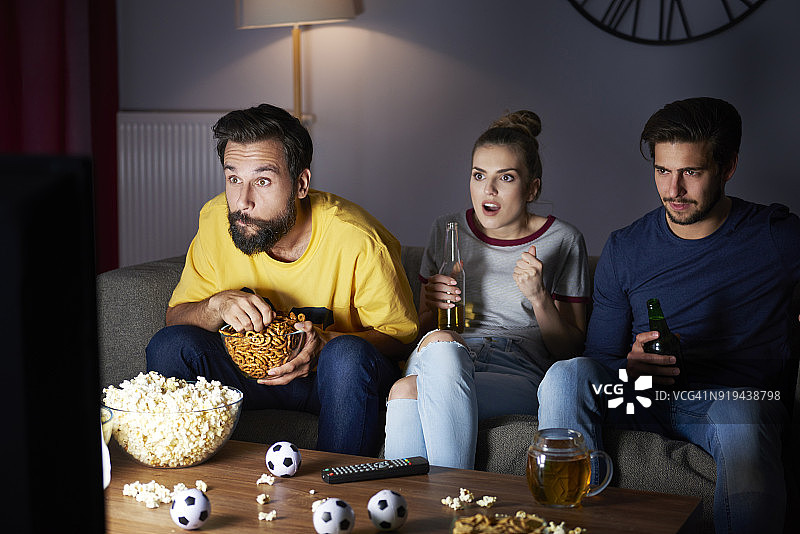 兴奋的朋友坐在沙发上看电视图片素材