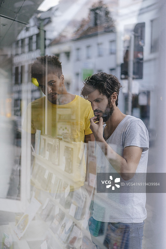 两个朋友在城市里看书店的橱窗图片素材