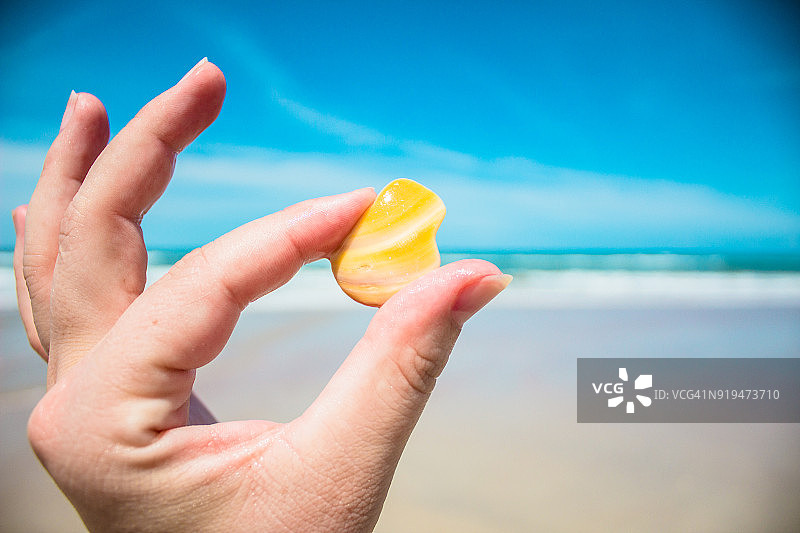 手持黄色岩石，背景是海滩风光图片素材