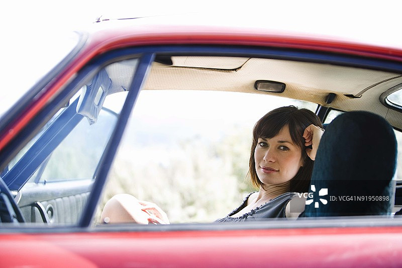 坐在红色汽车里的棕发年轻女人图片素材