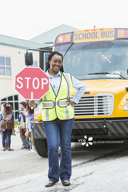 校车前的交通协管员举着停车标志图片素材