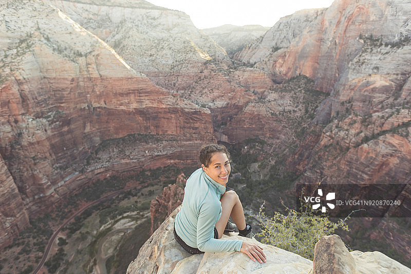 年轻女子坐在悬崖边俯瞰高速公路图片素材