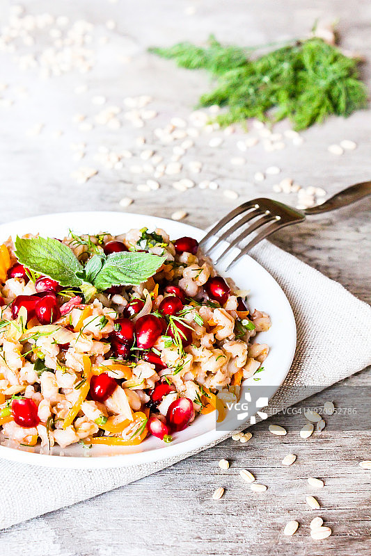 温暖的沙拉与大麦，胡萝卜，洋葱，石榴籽和新鲜薄荷图片素材