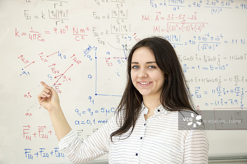 在白板前书写数学公式的女学生图片素材