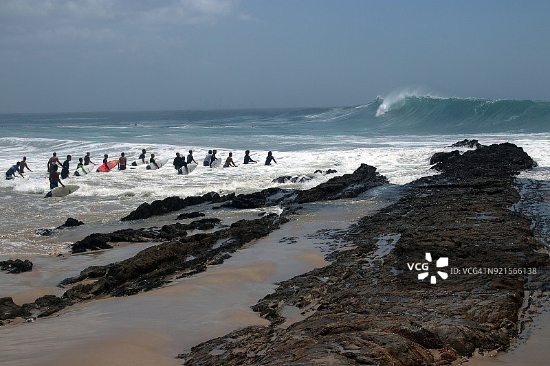 冲浪者等待在吉塔气旋期间于鲷鱼岩大浪中划出的机会图片素材