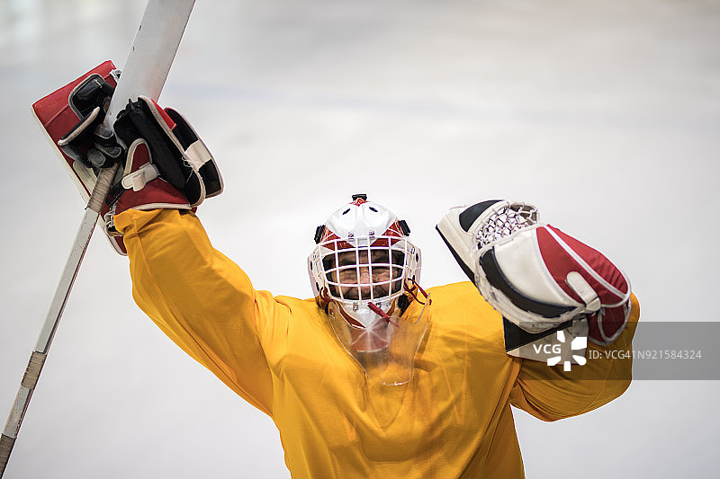 成功的冰球守门员举起双臂庆祝胜利。图片素材