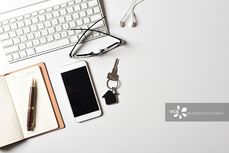 房地产中介工作场所：电脑键盘、房屋钥匙，智能手机俯视图图片素材