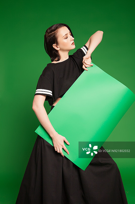 拿着绿色薄纸的黑衣女孩图片素材