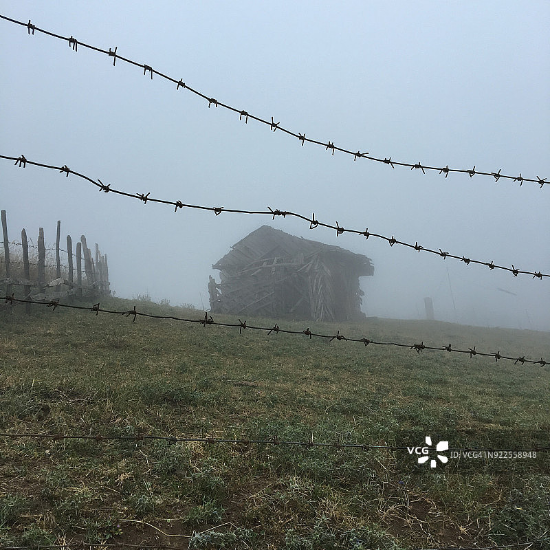 雾中带刺铁丝网的乡村老房子图片素材