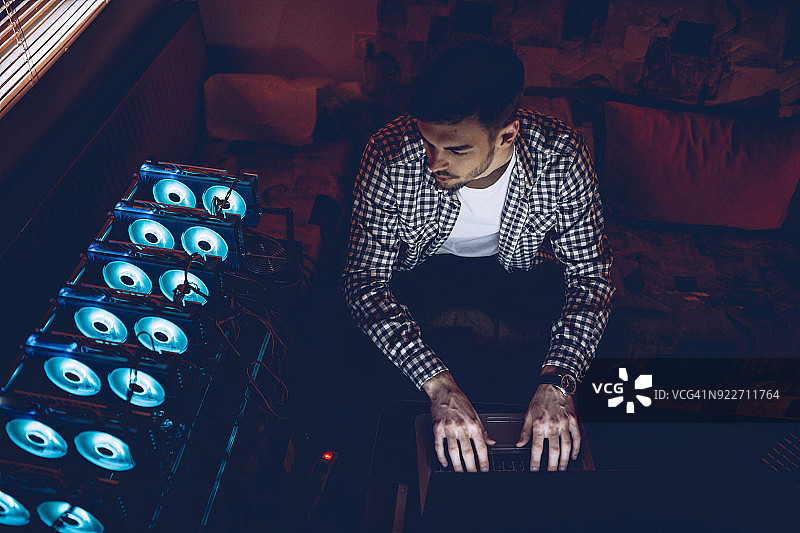 使用笔记本电脑进行虚拟货币挖矿的男人图片素材