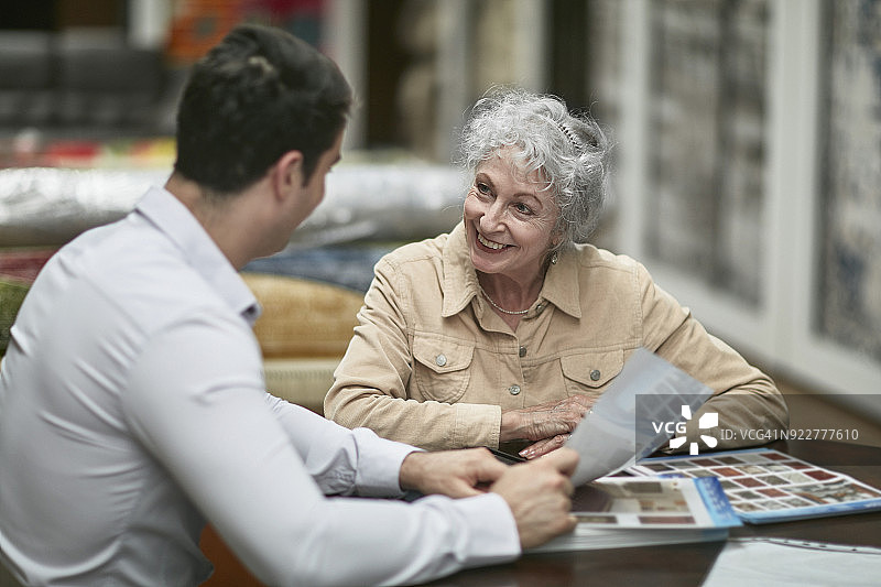 向微笑的顾客展示地毯设计的商人图片素材