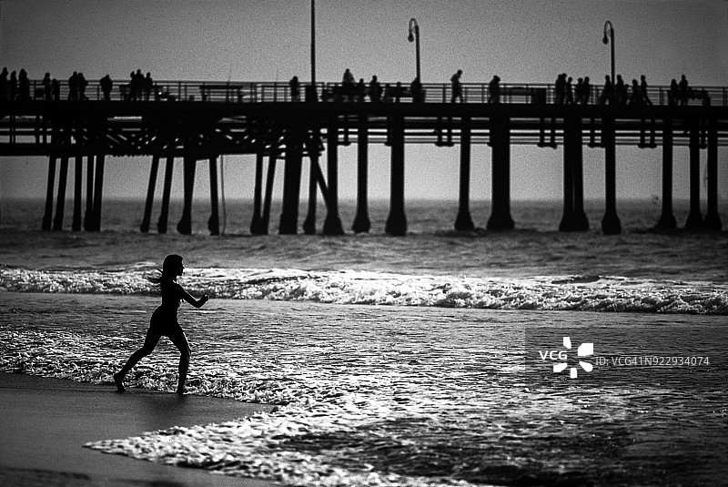 海滩上的女人剪影，背景是美国加利福尼亚州圣莫尼卡码头图片素材