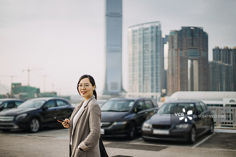 自信的亚洲女性在城市风景中使用智能手机图片素材