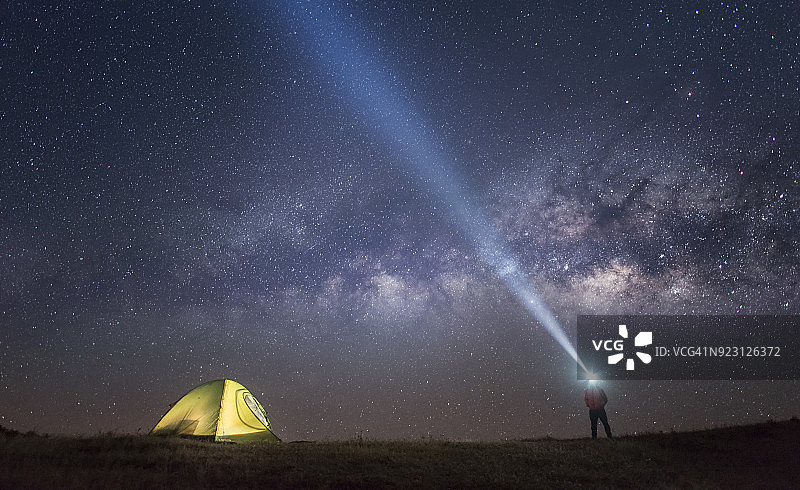 星空银河下的露营帐篷和手电筒人群图片素材