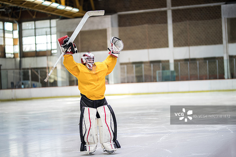 快乐的冰球守门员在冰场上庆祝他的成功图片素材