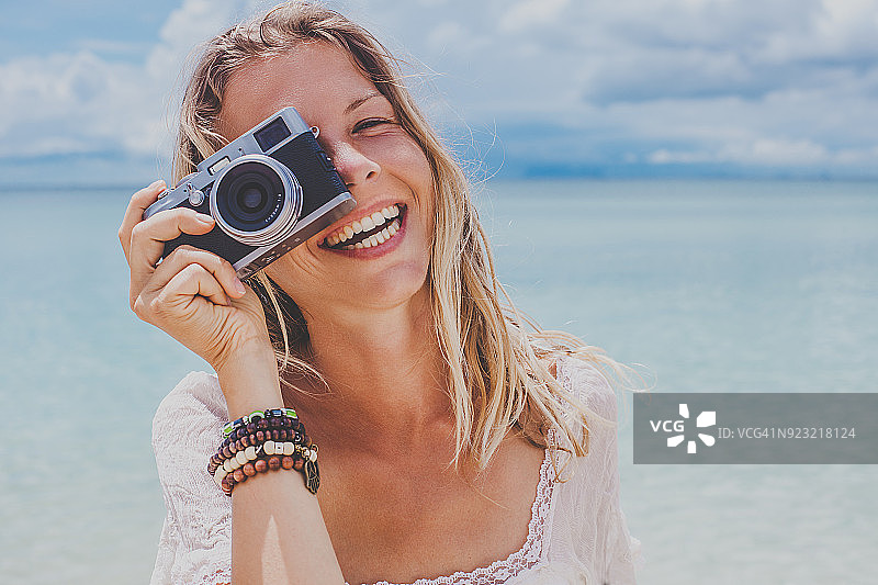 女孩用胶片相机在海边拍照图片素材