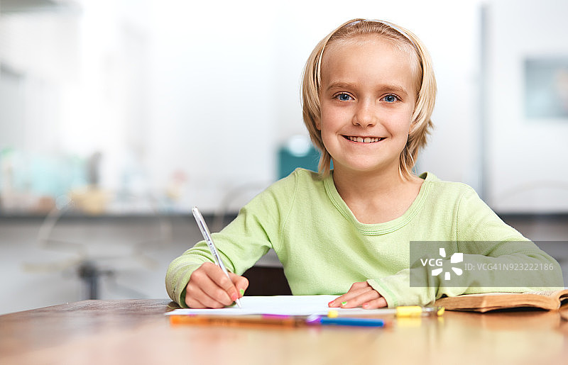 认真做作业，灿烂微笑的可爱金发女学生图片素材