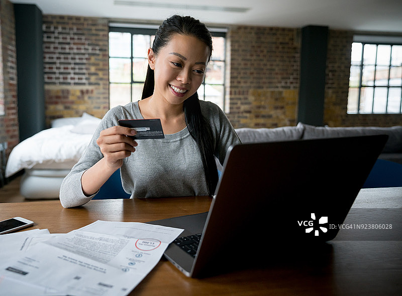 亚洲女人在家网上购物。图片素材