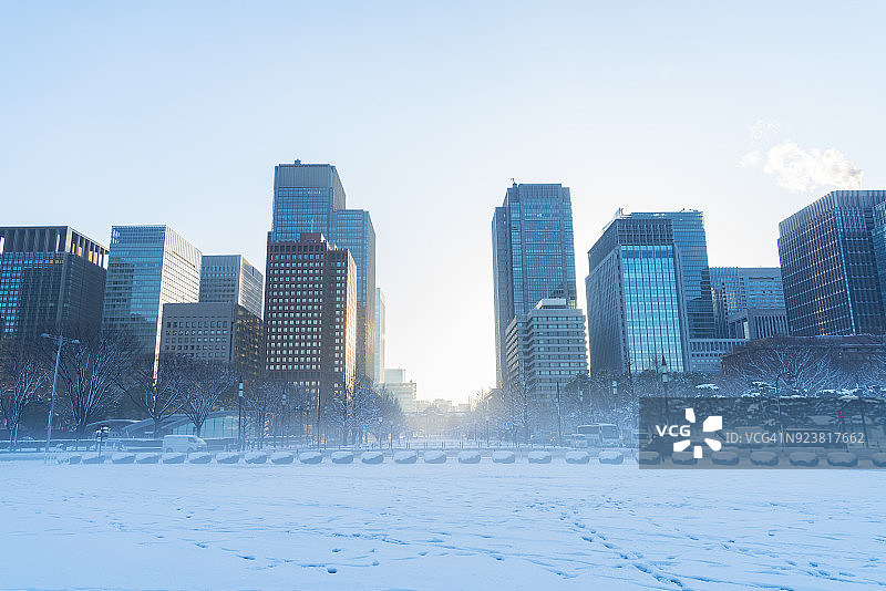 冬季暴风雪后的东京千代田区清晨：丸之内区摩天大楼、皇居外苑和雾中的天空图片素材