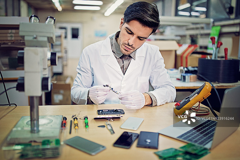 男子在维修店修理手机图片素材