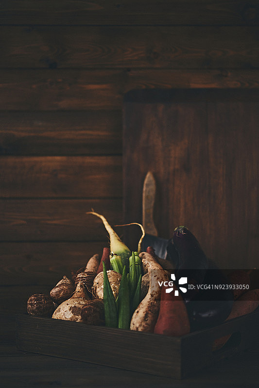 在昏暗光线下拍摄的蔬菜箱和砧板静物图片素材