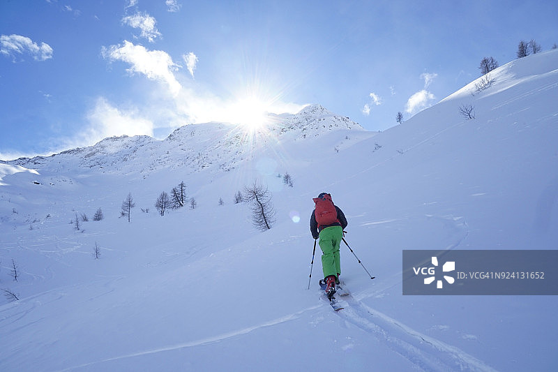 滑雪者在雪后攀登陡峭山坡图片素材
