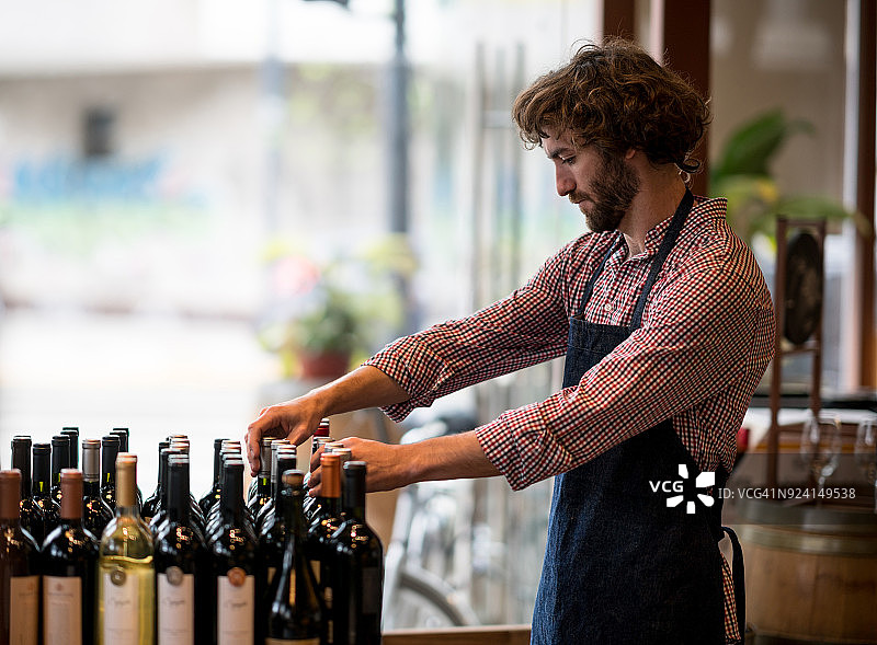 年轻男人在酒庄整理酒瓶，表情严肃图片素材